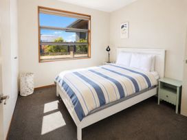A bedroom with a bed and nightstand at Infinity Views - Modern Wanaka Holiday Home in Wanaka