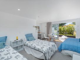 A bedroom with two beds and a table at Patton's Place - Pauanui