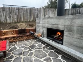 An outdoor area with a fireplace and benches at Lake Hawea Haven - Lake Hawea