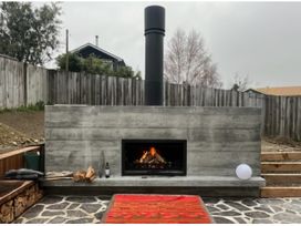 An outdoor area with a stone patio and a fireplace at Lake Hawea Haven - Lake Hawea