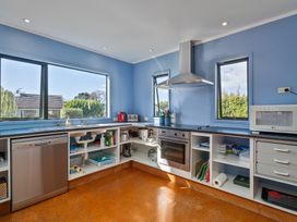 A kitchen with appliances and windows at Rosemary Cottage - Hahei Holiday Home