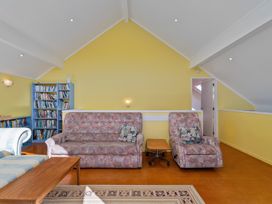A living room with a sofa and bookshelf at Rosemary Cottage - Hahei Holiday Home Hahei