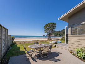 An outdoor area with a table and chairs overlooking the beach at Beachfront Beauty - Whangamata Beachfront Home, Whangamata