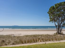 A beach view with sand and grass at Beachfront Beauty - Whangamata Beachfront Home, Whangamata