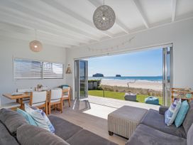 A living room with a sofa and dining area at Beachfront Beauty - Whangamata Beachfront Home Whangamata