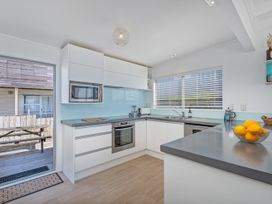 A kitchen with white cabinets and lemons on the counter at Beachfront Beauty - Whangamata Beachfront Home Whangamata