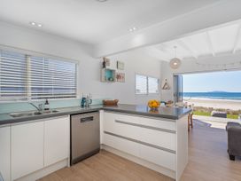A kitchen with a sink and dishwasher facing a beach at Beachfront Beauty - Whangamata Beachfront Home, Whangamata