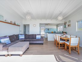 A living room with a sofa and dining area at Beachfront Beauty - Whangamata Beachfront Home, Whangamata
