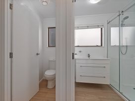 A bathroom with a toilet and sink next to shower at Beachfront Beauty - Whangamata Beachfront Home in Whangamata