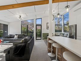 A living room area with sofas and a kitchen counter at Merioneth Retreat - Arrowtown Holiday Home in Abel Tasman National Park