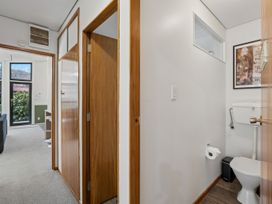 A bathroom with a toilet and mirror at Merioneth Retreat - Arrowtown Holiday Home Abel Tasman National Park