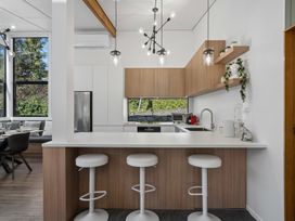 A kitchen with bar stools and a refrigerator at Merioneth Retreat - Arrowtown Holiday Home in Abel Tasman National Park