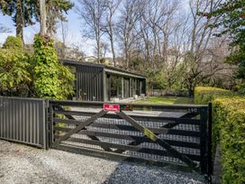 An outdoor area with a black gate and a modern house at Merioneth Retreat - Arrowtown Holiday Home Abel Tasman National Park