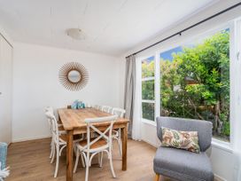 A dining table with chairs and a mirror in Slice of Pauanui - Pauanui