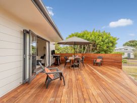 An outdoor area with a table and chairs on a wooden deck at Slice of Pauanui - Pauanui