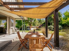 An outdoor patio with a wooden dining table and chairs under a canopy at Lake Hawea Hideaway in Lake Hawea