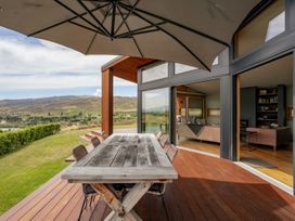 An outdoor patio with table and chairs near the sliding glass door at Vino and Views - Bannockburn Holiday Home