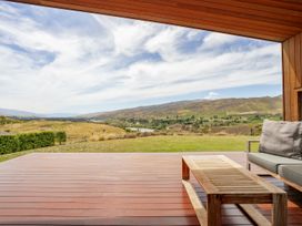 A deck area with a table and couch overlooking a landscape at Vino and Views - Bannockburn Holiday Home, Cromwell