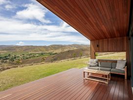 An outdoor seating area with a sofa and table overlooking mountains at Vino and Views - Bannockburn Holiday Home, Cromwell