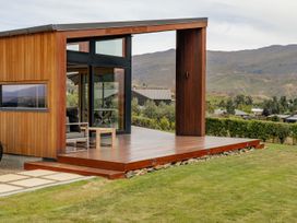 A wooden structure with glass panels and deck at Vino and Views - Bannockburn Holiday Home, Cromwell