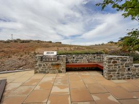 An outdoor area with a grill and stone wall at Vino and Views - Bannockburn Holiday Home, Cromwell