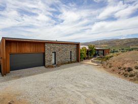 A house with a garage and stone features at Vino and Views - Bannockburn Holiday Home Cromwell