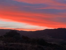 A sunset with colorful clouds over mountains at Vino and Views - Bannockburn Holiday Home in Cromwell