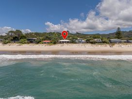 A beachfront view with houses and trees at Poppy's Beach House - Beachfront Whangapoua Home Whangapoua
