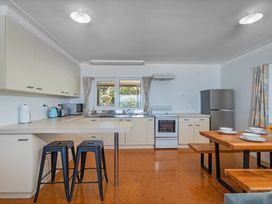 A kitchen with appliances and dining area at Poppy's Beach House - Beachfront Whangapoua Home Whangapoua