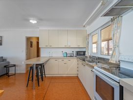 A kitchen with modern appliances and bar stools at Poppy's Beach House - Beachfront Whangapoua Home