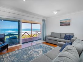A living room with a sofa and window view at Poppy's Beach House - Beachfront Whangapoua Home
