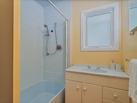 A bathroom with a shower and bathtub at Poppy's Beach House - Beachfront Whangapoua Home