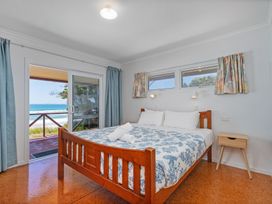A bedroom with a bed and sliding door at Poppy's Beach House - Beachfront Whangapoua Home