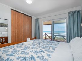 A bedroom with a bed and sliding door at Poppy's Beach House - Beachfront Whangapoua Home, Whangapoua