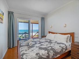 A bedroom with a bed and window overlooking the beach at Poppy's Beach House - Beachfront Whangapoua Home Whangapoua