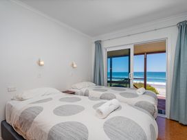 A bedroom with two beds and a view of the beach at Poppy's Beach House - Beachfront Whangapoua Home Whangapoua
