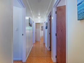 A hallway with multiple doors and wall art at Poppy's Beach House - Beachfront Whangapoua Home