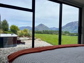 A bedroom with a hot tub and mountain view at A Remarkable Stay - Jack's Point Holiday Home, Queenstown