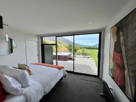 A bedroom with a bed and a hot tub visible through the window at A Remarkable Stay - Jack's Point Holiday Home in Queenstown