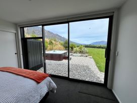 A bedroom with a view of a garden and hot tub at A Remarkable Stay - Jack's Point Holiday Home, Queenstown
