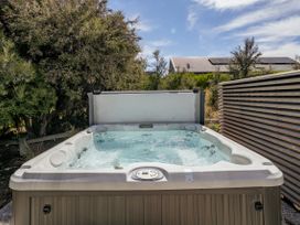 A hot tub with water and cover outdoors at Bull Ridge Escape - Wanaka Holiday Home in Wanaka