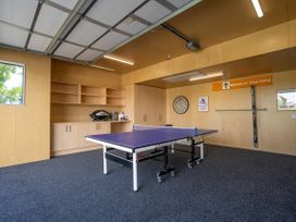 A game room with a ping pong table and storage shelves at Bull Ridge Escape - Wanaka
