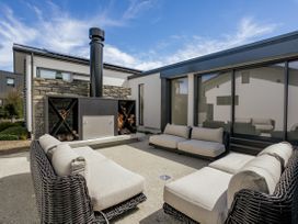 An outdoor seating area with a fireplace and sofas at Bull Ridge Escape - Wanaka Holiday Home, Wanaka