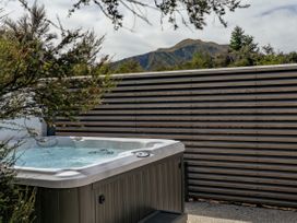 A hot tub with a wooden fence and mountains in the background at Bull Ridge Escape - Wanaka