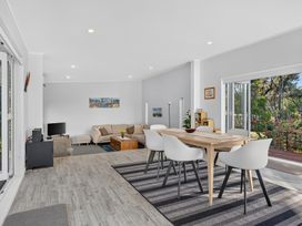A living room with sofa and dining area at Pohutukawa Peace - Mangawhai Holiday Home, Mangawhai Village