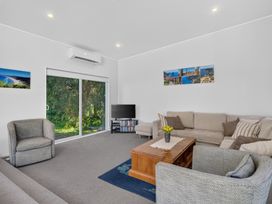 A living room with furniture and a television at Pohutukawa Peace - Mangawhai Holiday Home in Mangawhai Village