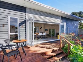 An outdoor seating area with a table and chairs at Pohutukawa Peace - Mangawhai Holiday Home, Mangawhai Village