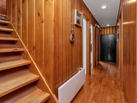 A hallway with wooden stairs and wall panels at Matapouri Magic - Matapouri