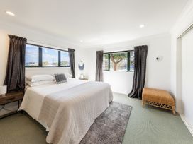 A bedroom with a bed and windows at Manaia Magic - Tairua Holiday Home, Tairua