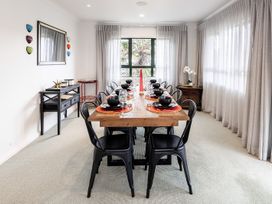 A dining room with a wooden table and black chairs at Manaia Magic - Tairua Holiday Home in Tairua